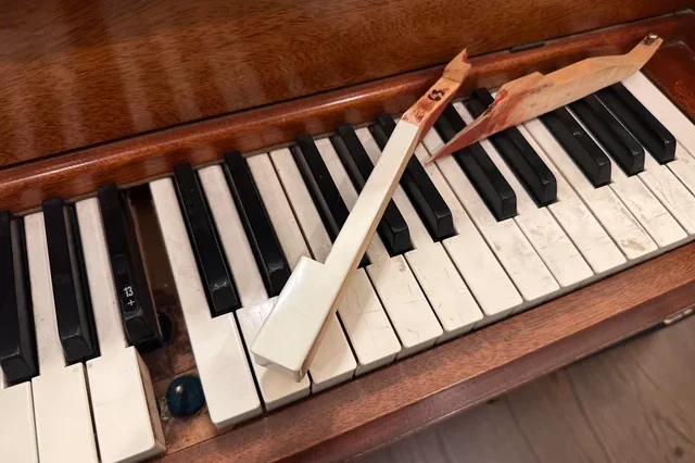 Close-up view of a dilapidated antique piano keyboard with cracked, uneven ivory keys.